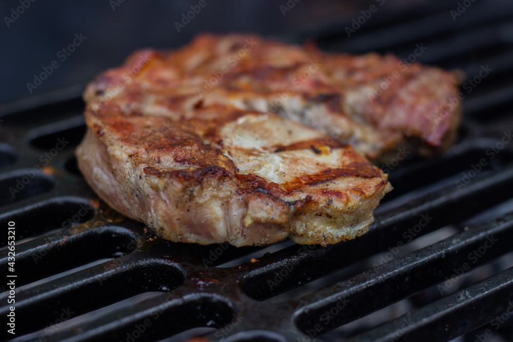 Delicious pork steak is cooked on a cast iron wire rack Delicious pork steak is cooked on a cast iron wire rack