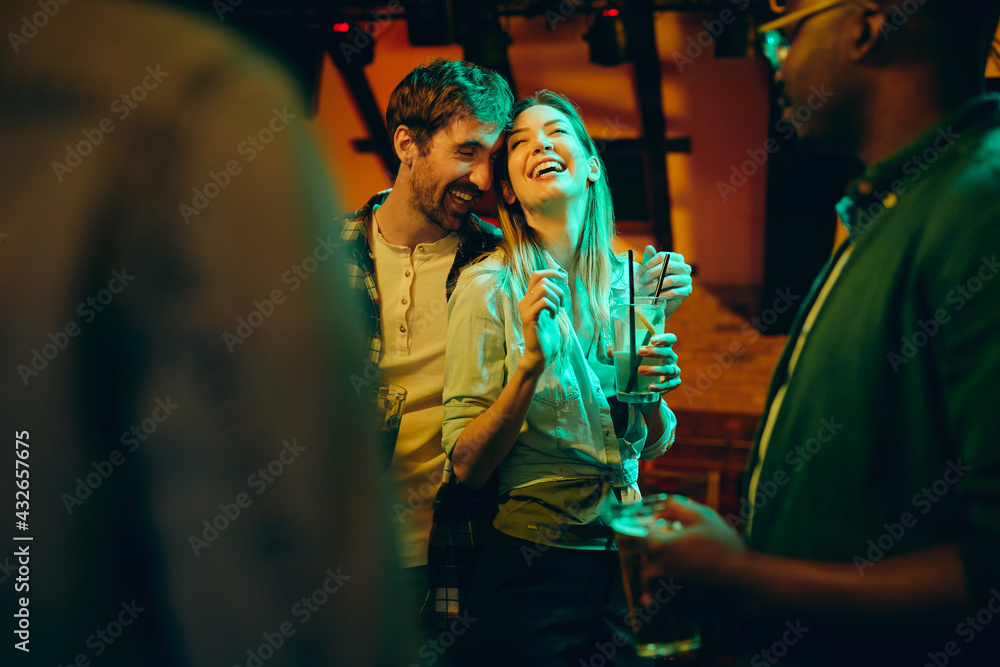 Young carefree couple having fun during night date in a bar.