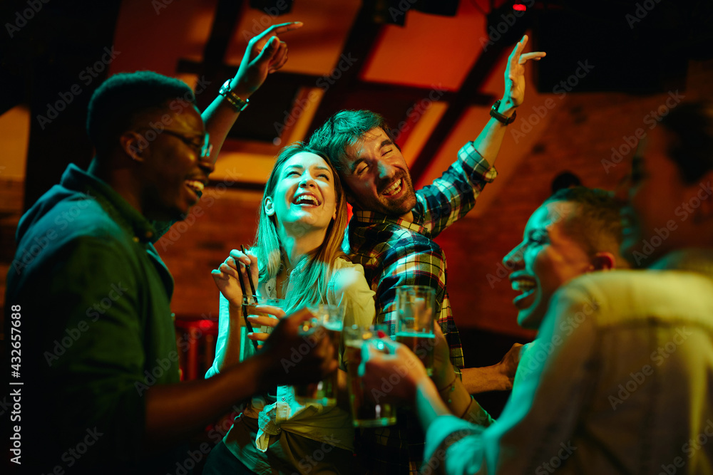 Group of cheerful friends drinking and dancing while gathering in pub at night. Group of cheerful friends drinking and dancing while gathering in pub at night.
