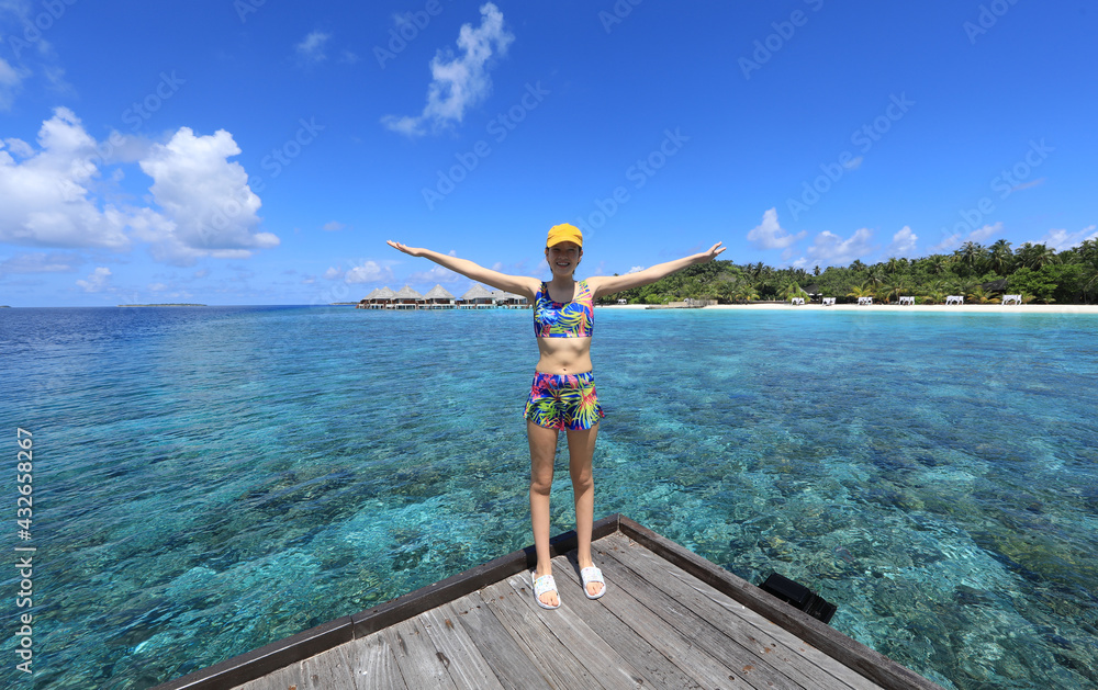 Naklejka premium teenage girl in a swimsuit on the shore of a tropical island