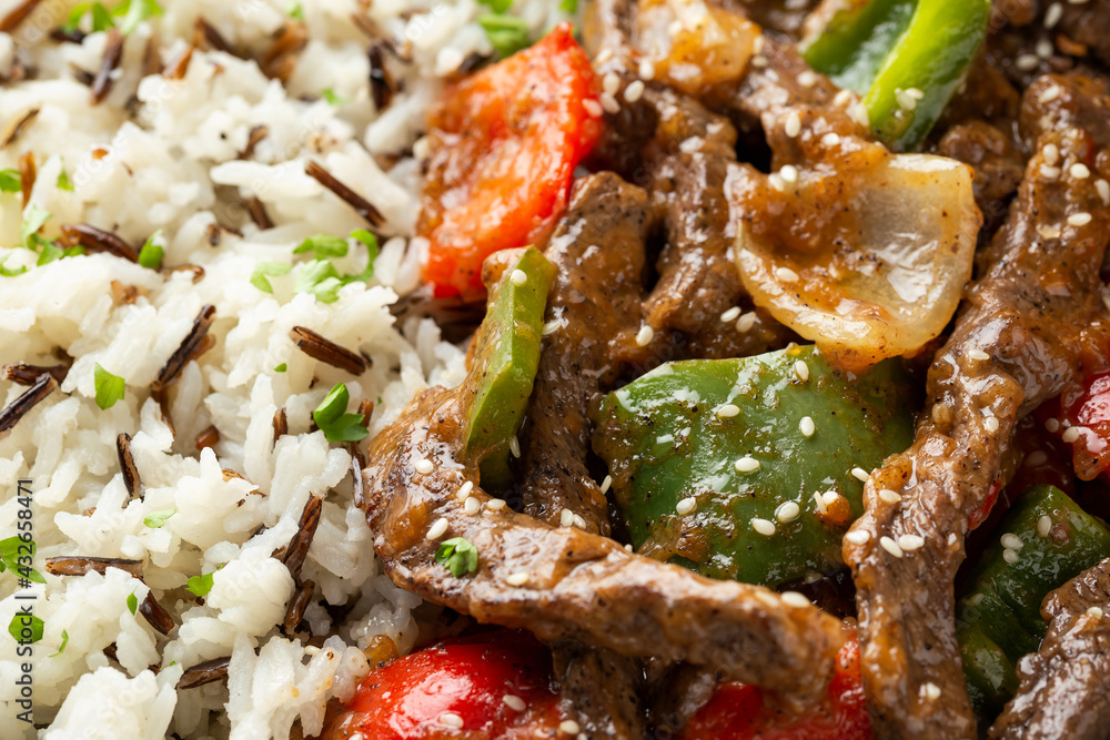 Stir fry Chinese pepper beef steak with onion, red and green bell pepper, rice in bowl Stir fry Chinese pepper beef steak with onion, red and green bell pepper, rice in bowl