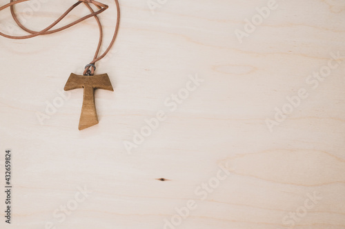 Cuadro en lienzo Top view of a wooden tau cross necklace on a wooden surface for a copy space