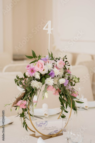 Centerpiece made of green leaves and fresh flowers stands on the dinner table. Wedding day. Fresh flowers decorations. © Mihai