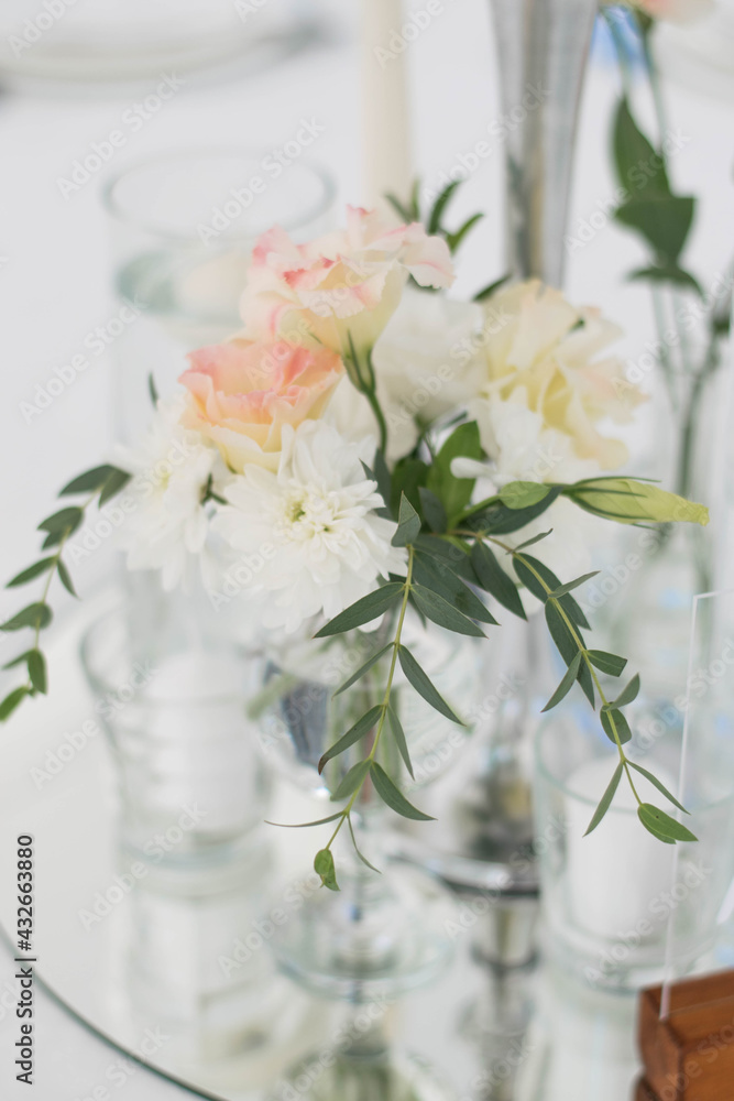 Close-up of a wedding dinner table at reception. Fresh flowers and candles on mirros plate. Wedding decorations. Close-up of a wedding dinner table at reception. Fresh flowers and candles on mirros plate. Wedding decorations.