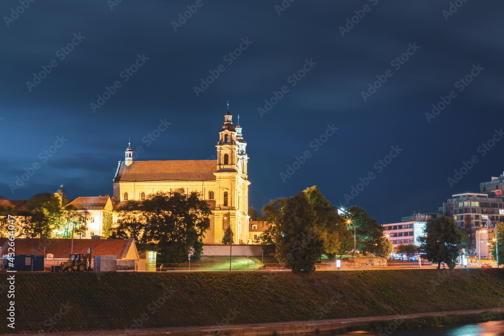 Vilnius, Lithuania, Eastern Europe. Night View Of Catholic Church Of St. Raphael The Archangel In Vilnius, Lithuania. Illuminated Street