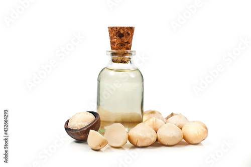 Macadamia nuts heap and macadamia oil in glass bottle isolated on a white background.