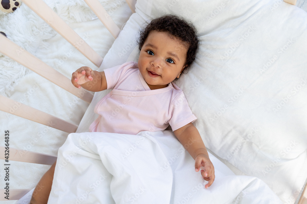 african american baby boy in the crib goes to bed or wakes up in the morning and smiles in the bedroom african american baby boy in the crib goes to bed or wakes up in the morning and smiles in the bedroom