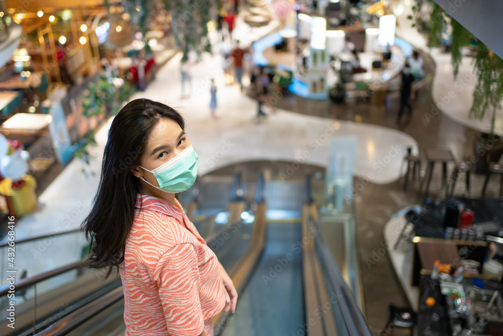 Adult Asian women wearing surgical face mask using mobile phone in department store. New normal,  lifestyle that we need to protect our health from Corona virus. Stay safe and Social distance.