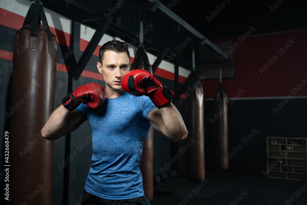 Shirtless handsome Caucasian men boxer with strong muscle training boxing punch in side of the gym with sandbag. Cardio sport workout activity for good health and build up body and physical strength.