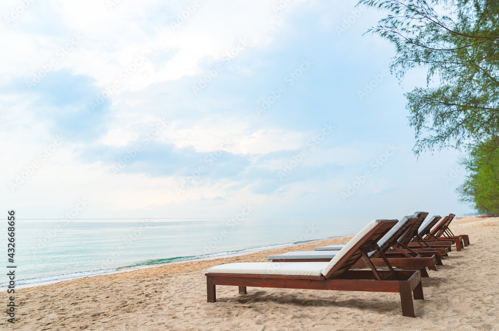 Wooden beach bed or sunbed beach on beautiful beach with turquoise ocean and blue sky, no people, perspective view with space for copy on sky, image of relax and calm on nature beach.