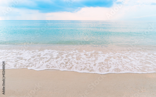 Beautiful paradise beachscape  turquoise color water  wave with white bubbles  blue sky with light in the morning  clean beach  reflection of sunlight in surface of sea  no people  wide image.