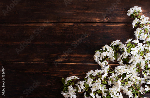 Background with branches of blossoming cherry on a dark wooden board, spring concept.