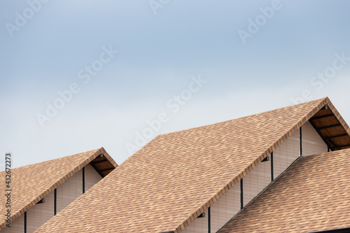 brown asphalt roof shingle background with blue sky.