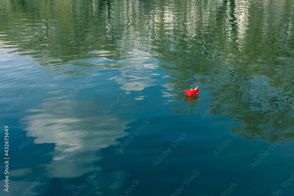 Red paper boat floats on the river