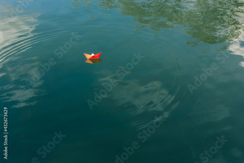 Red paper boat floats on the river