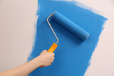 Woman painting wall with roller, closeup. Redecoration