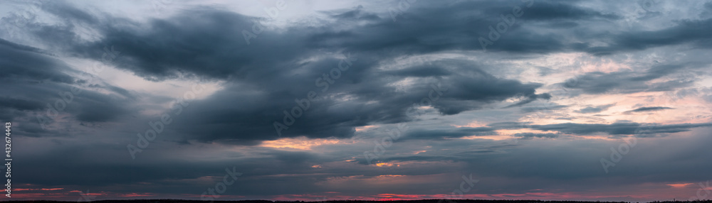 Dark sunset with gloomy clouds and red light on the horizon