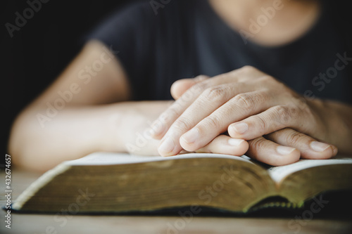 Hands folded in prayer on a Holy Bible