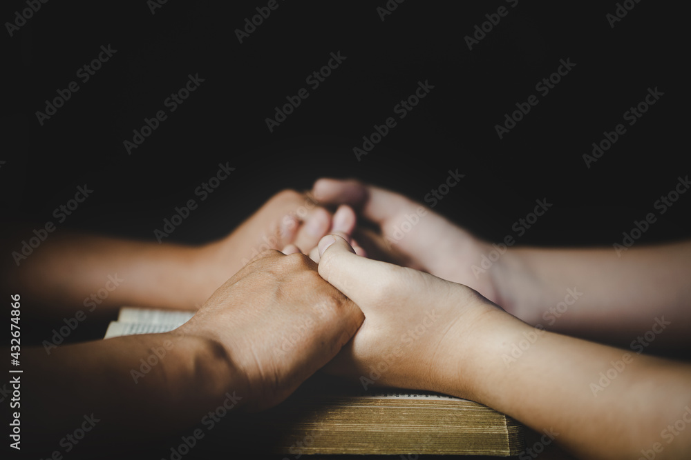 Hands folded in prayer on a Holy Bible Hands folded in prayer on a Holy Bible