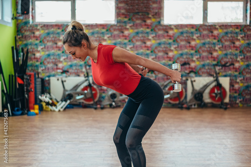 Woman holding dumbbells while training in the gym