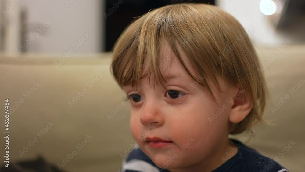Baby blond toddler sitting on sofa watching cartoon hypnotized by media Baby blond toddler sitting on sofa watching cartoon hypnotized by media