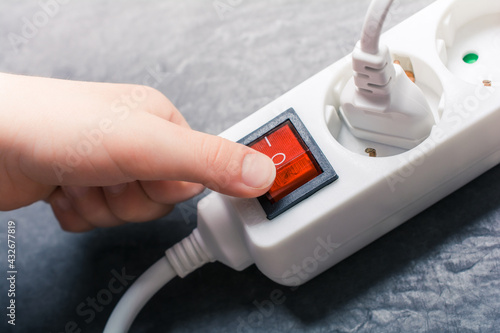 Child Hand Pressing Red Switch On A Power Strip - Prevent Child Hazard Concept photo