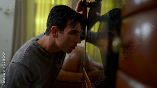 Side view of young Middle Eastern man controls baking process in oven at home. Portrait of confident handsome positive chef cooking in kitchen indoors. Baking and lifestyle photo