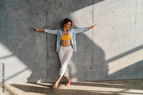 smiling happy beautiful woman posing against concrete wall on sunny day summer fashion style trend