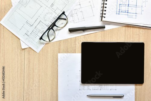 a top view of architect working desk with equipment for drawings pens sketched idea on wood table, the concept of modern technology for architectural working with tablet