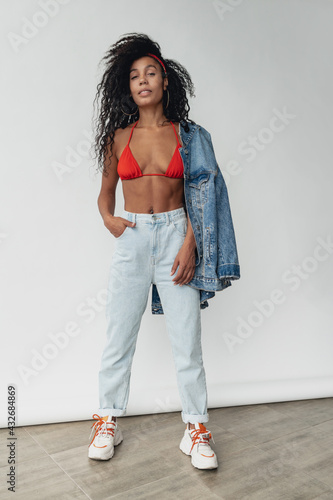 attractive black african american woman posing in stylish hipster outfit on white background