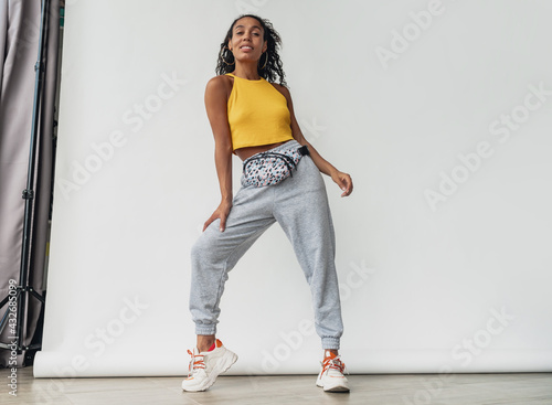attractive black african american woman posing in stylish hipster outfit on white background
