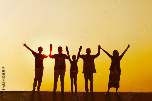 Three generation family standing with raised hands