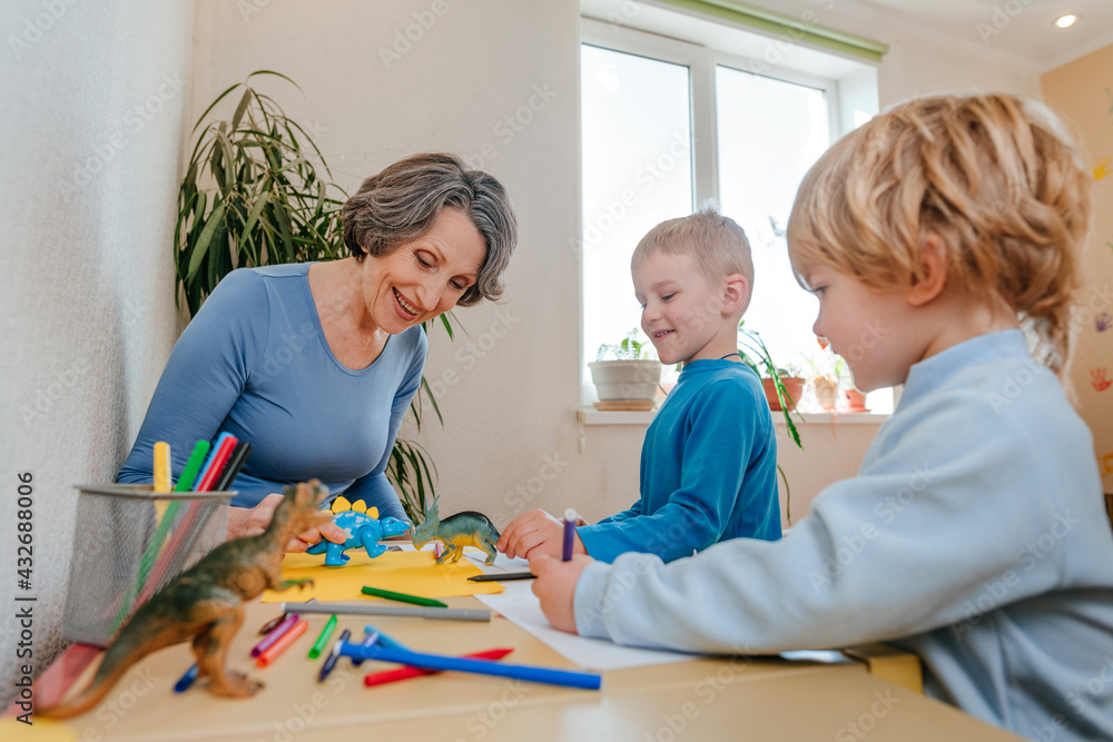 Fototapeta premium Boys playing with his grandmother with dinosaur toys