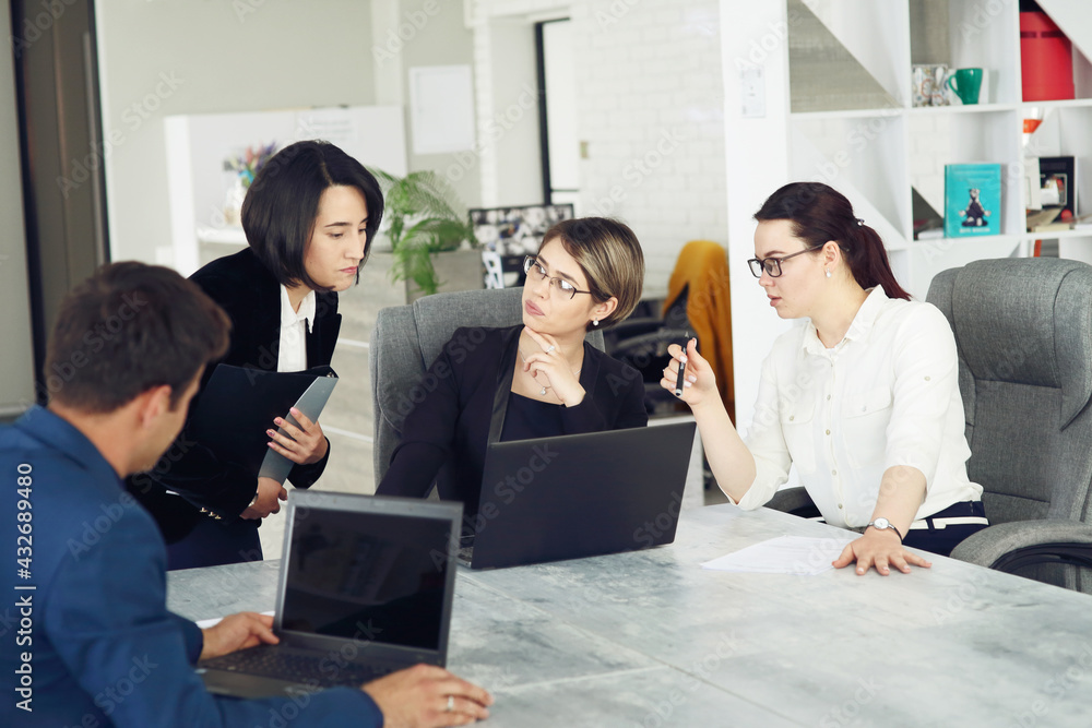 Fototapeta premium Three young successful business women in the office working together on a project