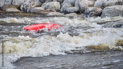 kayaker rolling and floating upside down after surfing a wave in the Poudre River Whitewater Park.