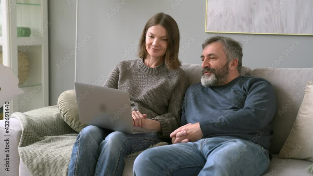 Medium Shot Of Attractive Middle Age Man with His Daughter. Caucasian Woman Explain To Father How To Use Laptop Medium Shot Of Attractive Middle Age Man with His Daughter. Caucasian Woman Explain To Father How To Use Laptop