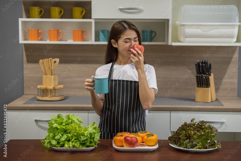 Happy young Asian woman cooking with fresh vegetable and fruit in the modern kitchen