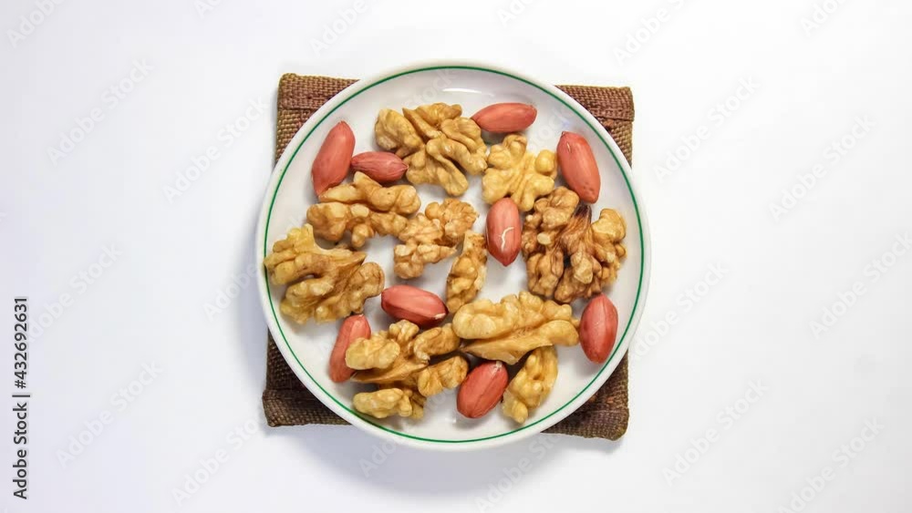 Stop motion animation. Peeled walnuts and peanuts move around the saucer. Top view. Stop motion animation. Peeled walnuts and peanuts move around the saucer. Top view.