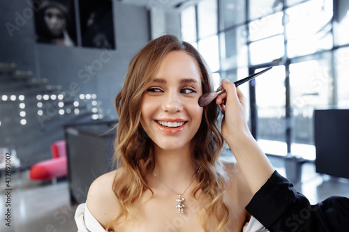 Young woman getting hair styling and makeup in a beauty salon.