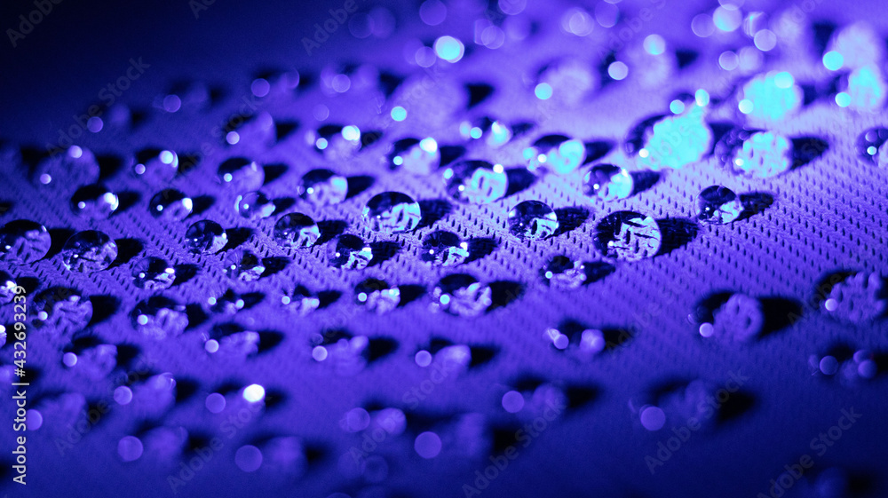 drops of water on a material platform with a dark blue color light shinning onto the area.