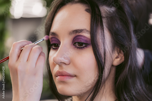 Young woman getting hair styling and makeup in a beauty salon.