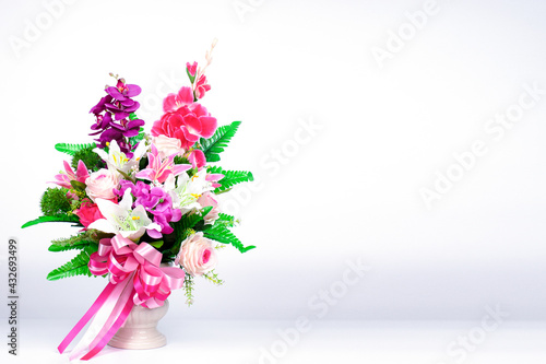 A beautiful bouquet of flowers in a vase that is placed on a table with a white backdrop.