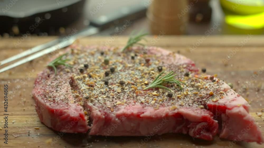 dropping and seasoning rib eye beef steak on wooden cutting board dropping and seasoning rib eye beef steak on wooden cutting board