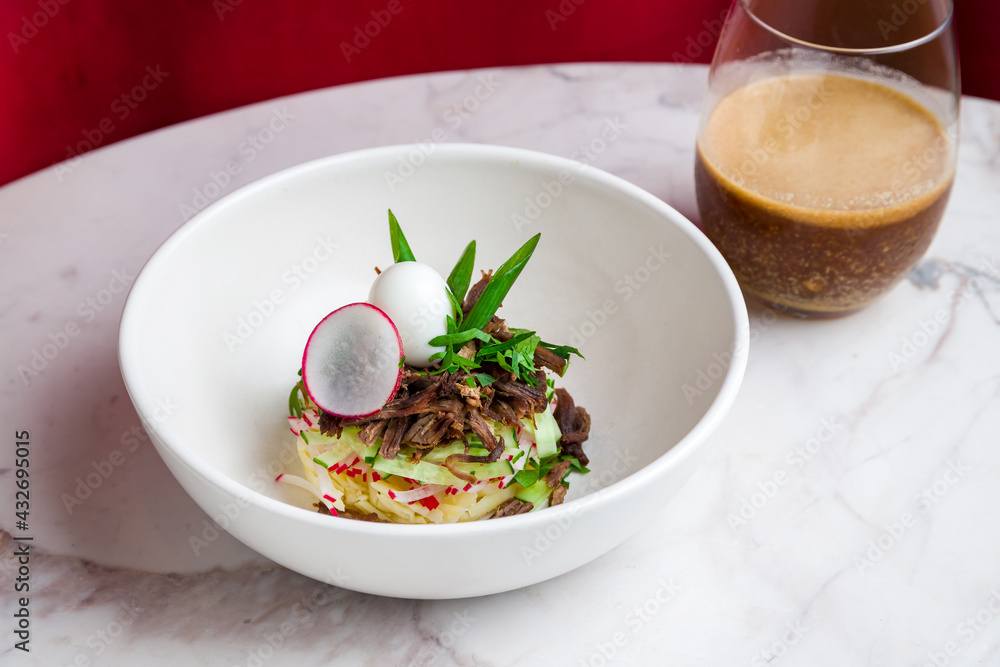 okroshka on kvass on white plate on marble table and red curtain at the back okroshka on kvass on white plate on marble table and red curtain at the back