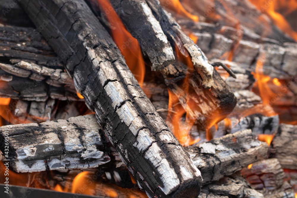 burning firewood stacked in a bonfire with coals in the open air and red flames burning firewood stacked in a bonfire with coals in the open air and red flames