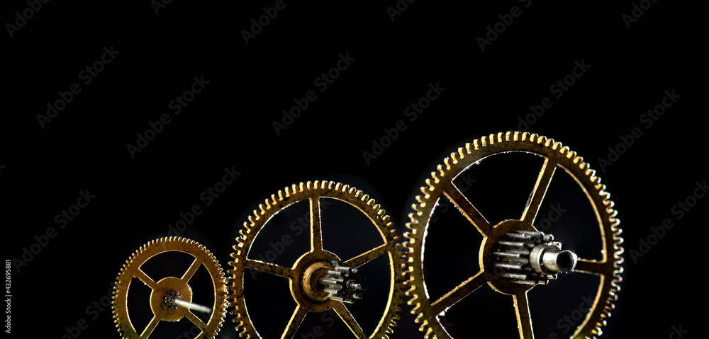 Obraz premium Three gears of different sizes on a black background. Panoramic photo.