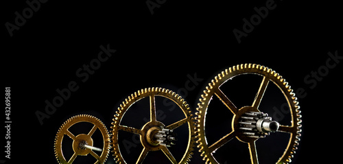 Three gears of different sizes on a black background. Panoramic photo.
