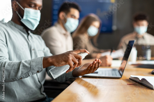 International workers wearing medical masks using sanitizer photo