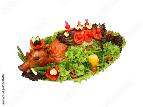Roasted piglet decorated with vegetables on platter isolated