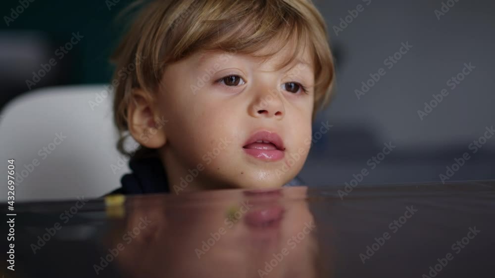 Baby toddler hypnotized by screen, kid biting table while watching
